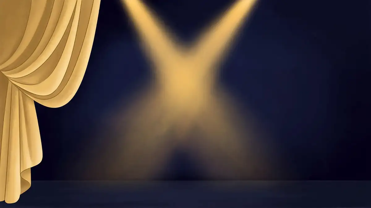 Golden stage spotlights crossing over a dark navy Broadway stage